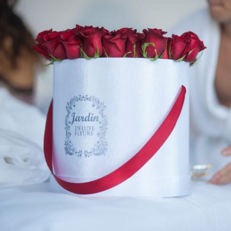 A large white signature hat box stuffed with fifty luxurious red roses, delivered to New York City and Miami customers.
