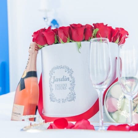 red rosses in a white hat box with champagne